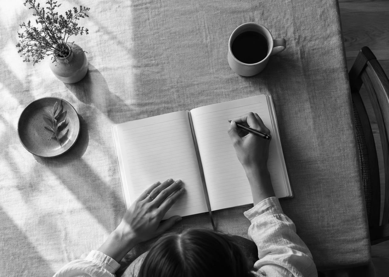 Hands writing in an intensive workbook at a linen-covered table